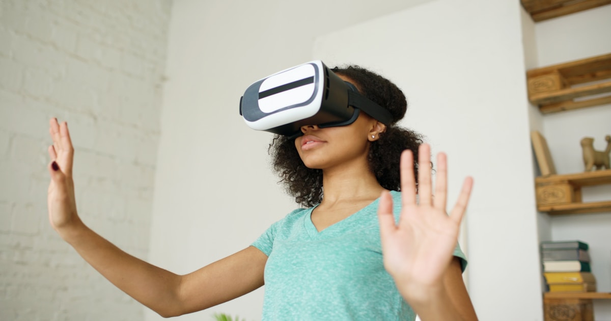 Young woman wearing vr headset, hands raised.