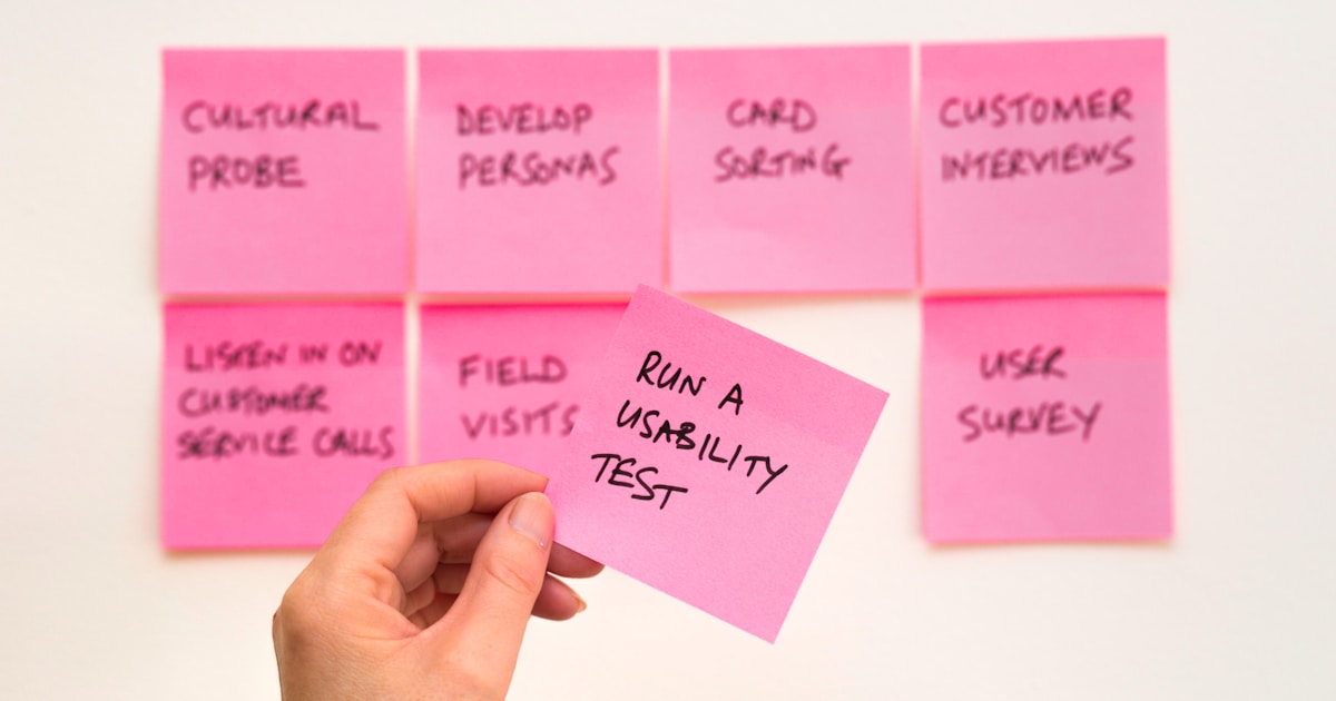 person holding pink sticky note